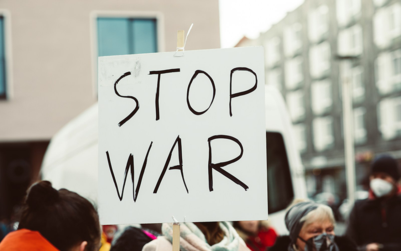 a sign that says stop war in front of a crowd of people